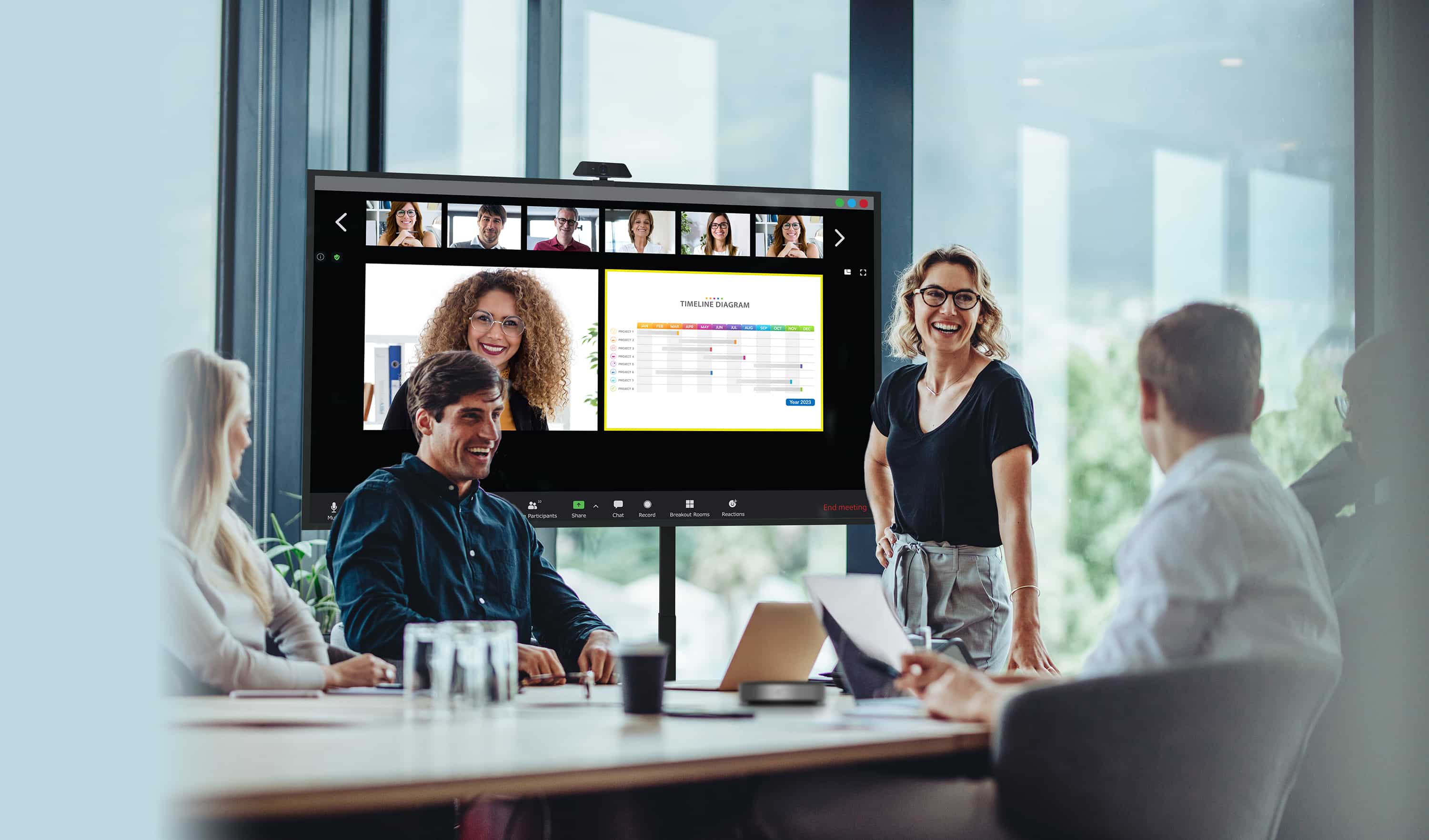Geschäftsleute, die eine Besprechung durchführen, bei der einige Mitarbeiter physisch anwesend sind, sie schauen auf ein Display der Optoma N-Serie, während ihre externen Kollegen auf dem Bildschirm neben den Inhalten, die sie teilen, angezeigt werden.